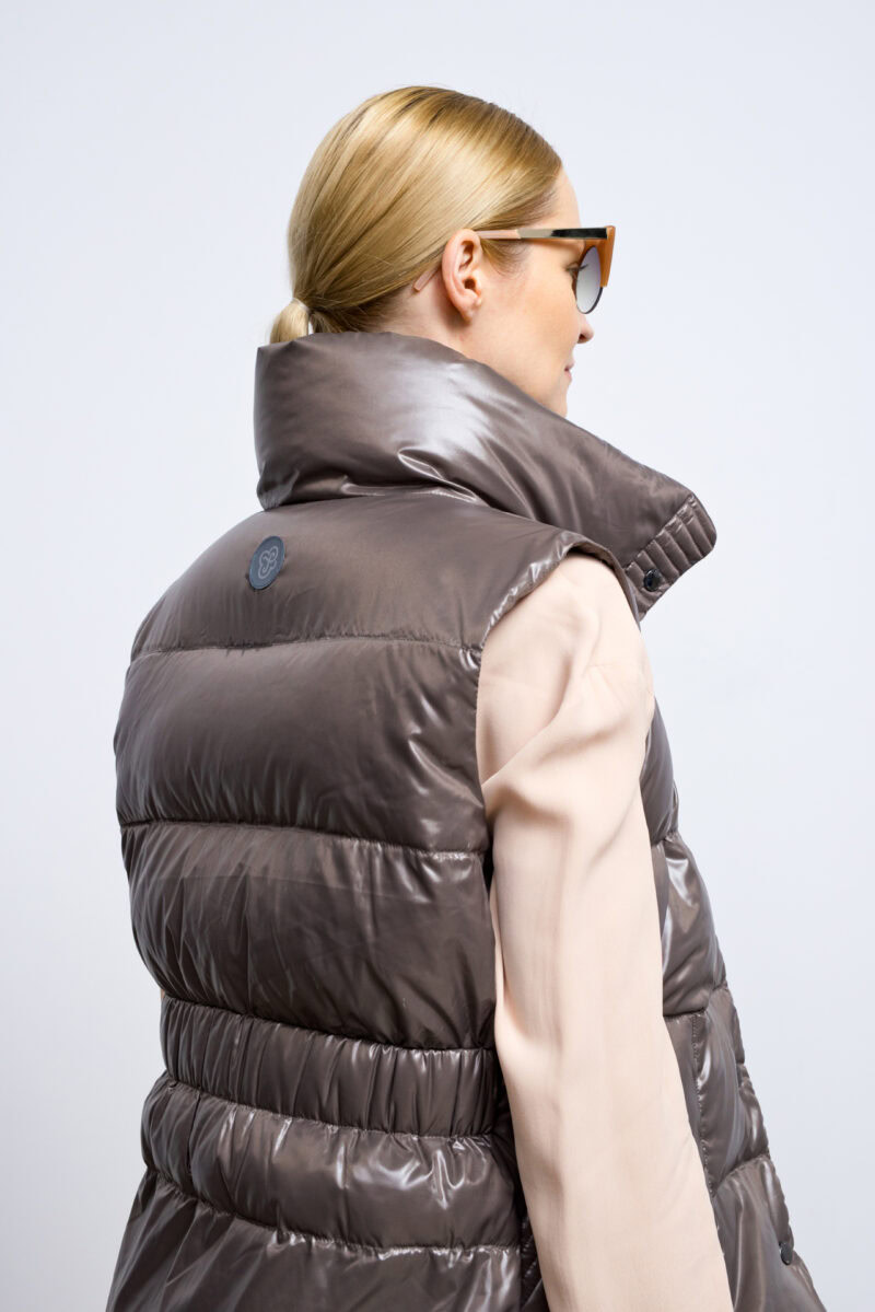 Marron brown vest with high collar and two front pockets. Zipper and stud fastening. Vest with an elastic waistband on the back and natural goose down filling.