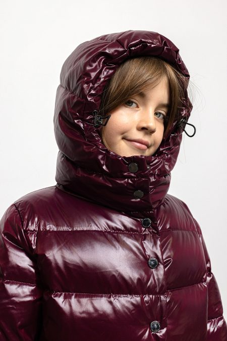 Girl in winter coat in burgundy colour, with hood on