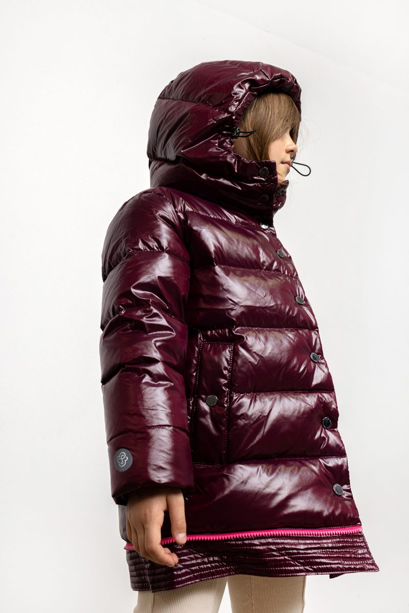 Girl in winter coat in burgundy colour, with pink zipper and hood