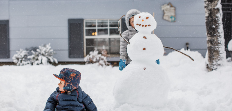 dzieci na śniegu w zimowych ubraniach, lepią bałwana