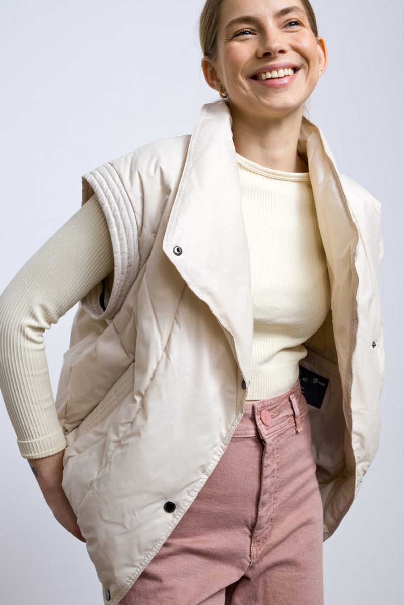 A light, transitional down jacket in ivory that can easily be turned into a vest - it has zippered sleeves. Filled with natural goose down, light and compact. Suitable for wearing all year round at temperatures above 5 degrees Celsius.