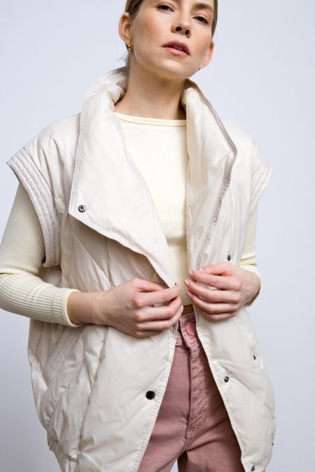 A light, transitional down jacket in ivory that can easily be turned into a vest - it has zippered sleeves. Filled with natural goose down, light and compact. Suitable for wearing all year round at temperatures above 5 degrees Celsius.