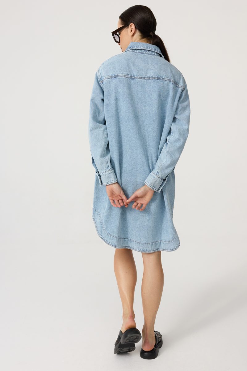 Denim dress with front and side pockets, light-washed denim, straight loose cut. Button fastening. Back view.