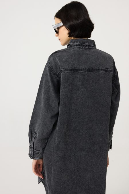 Denim dress with front and side pockets, black-washed denim, straight loose cut. Button fastening. Back view.